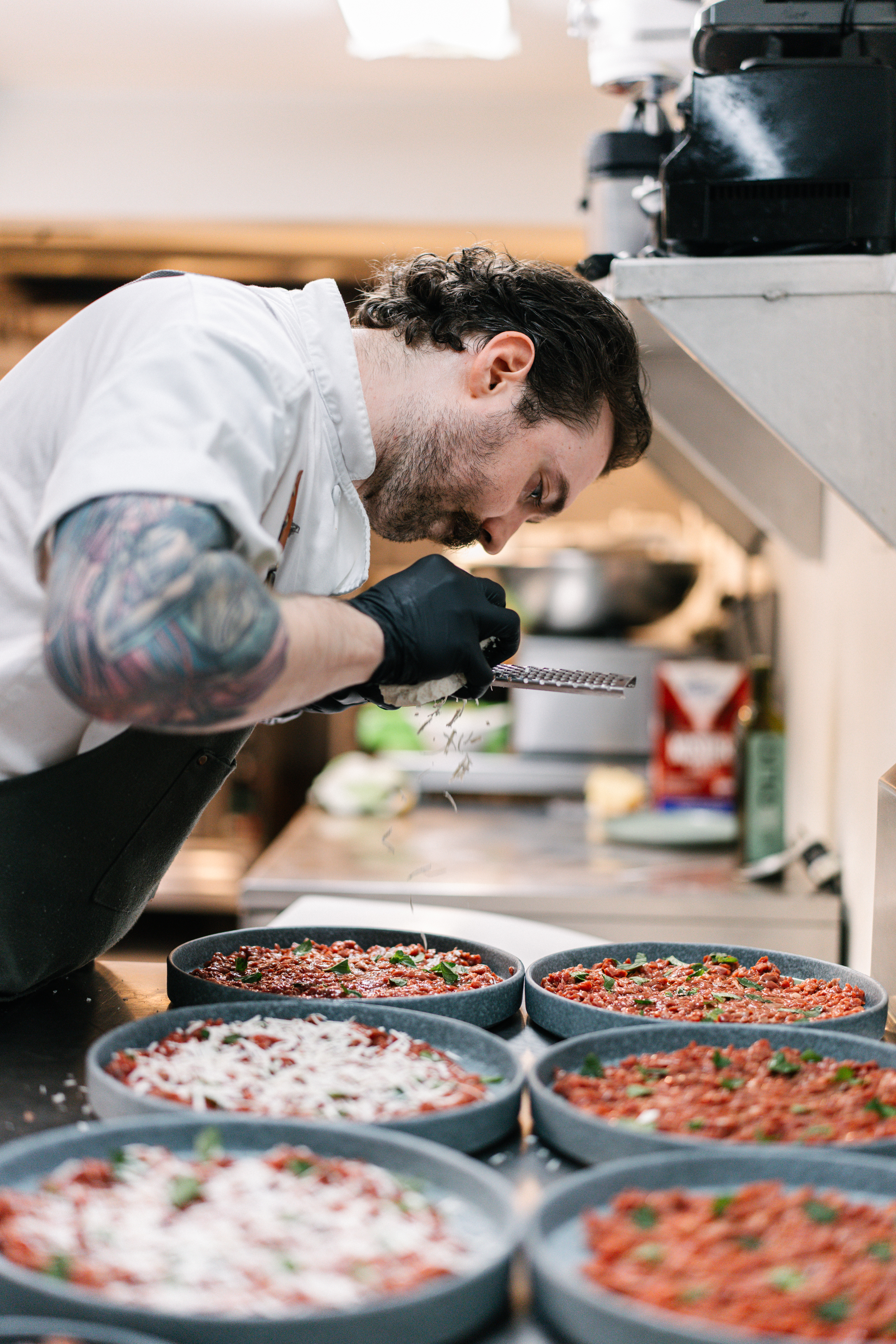 Chef Preparing Handmade Antipasto – Roscioli NYC Catering Chef grating fresh cheese over handmade Italian antipasto at Roscioli NYC kitchen.